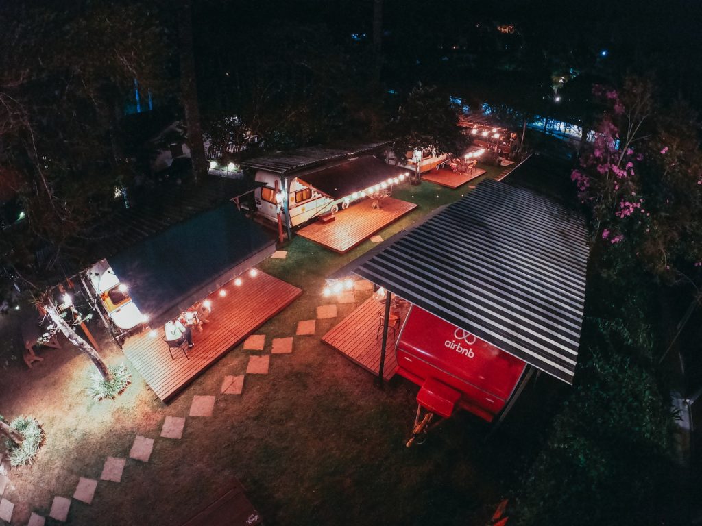 Aerial view of trailers for tourists at camping area decorated with sparkling garlands at night